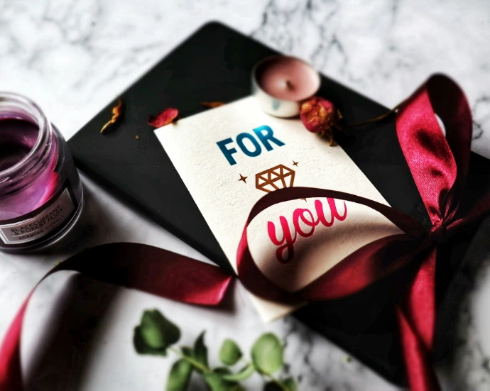greeting card beside a red ribbon and tealight candle